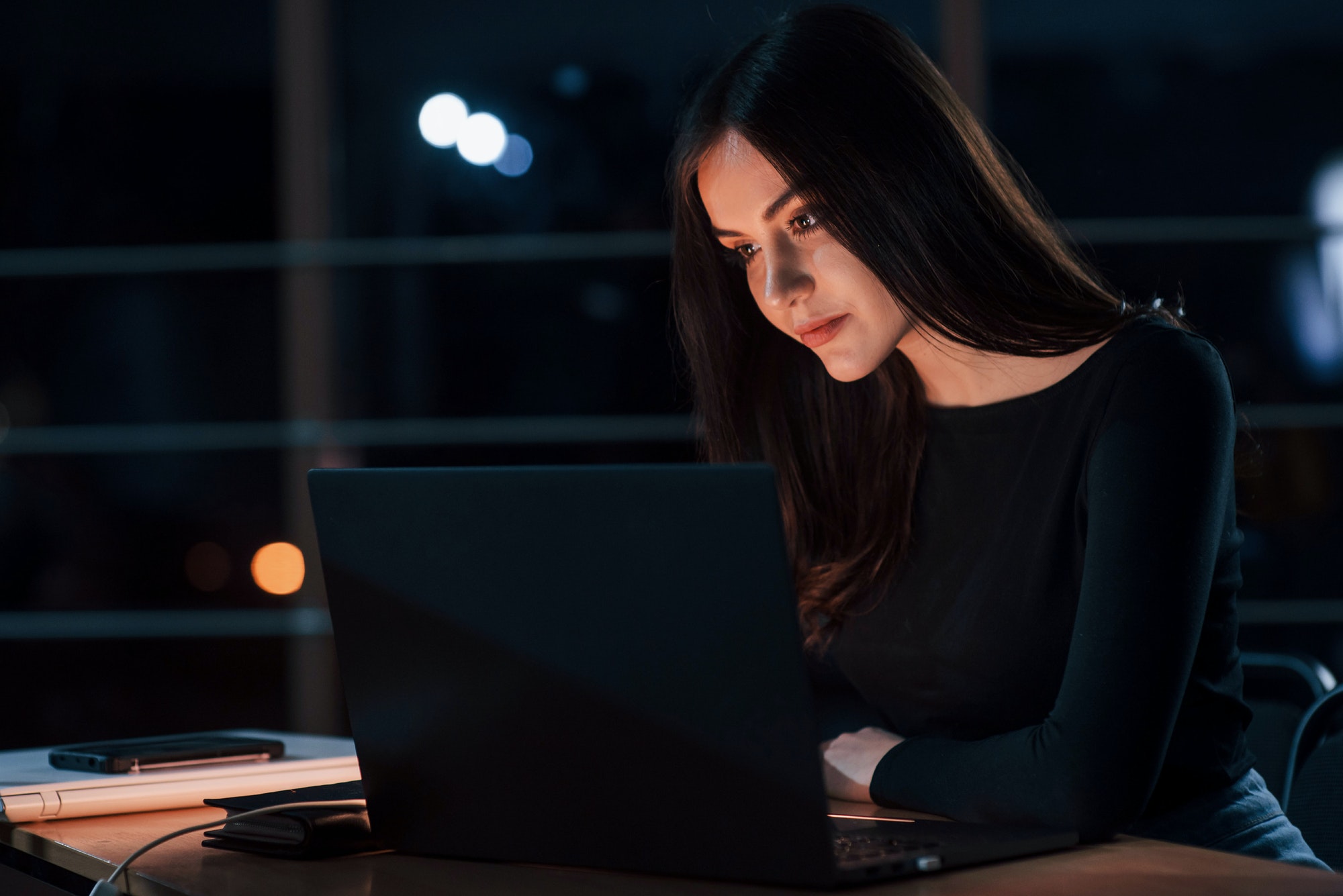 Attractive brunette businesswoman works alone in the office at nightime